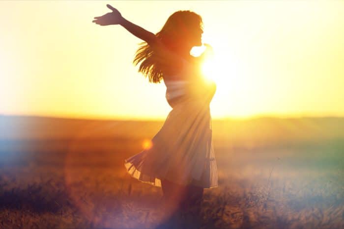 Frau im Sommerkleid Feld Sonnenuntergang Hände zum Himmel